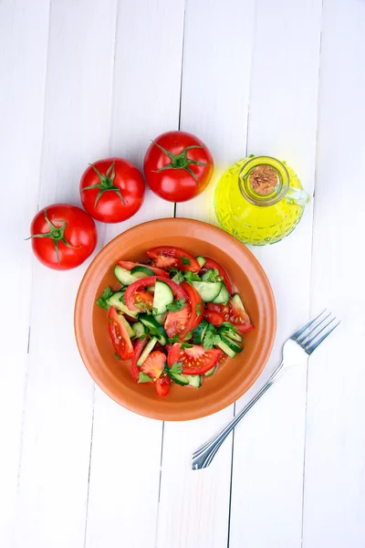 Verse salade met tomaten en komkommers op witte houten achtergrond — Stockfoto