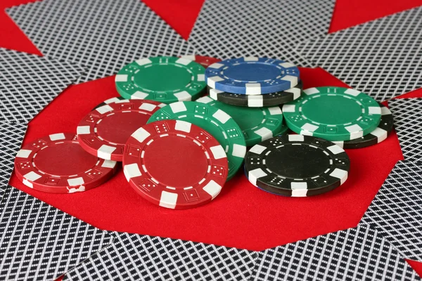 Poker chips e carte da gioco su un tavolo rosso — Foto Stock