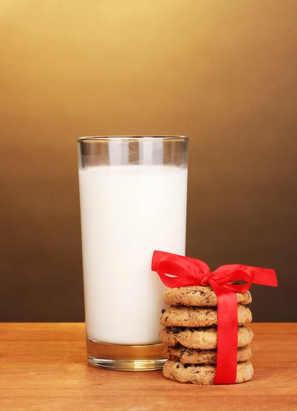 A tej és a cookie-kat a barna háttér fából készült asztal üveg — Stock Fotó