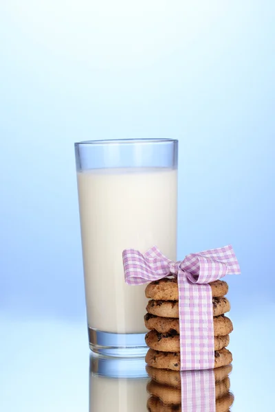 Vaso de leche y galletas sobre fondo azul — Foto de Stock