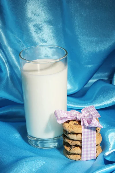 Ποτήρι γάλα και τα cookies σε φόντο μπλε ύφασμα — Φωτογραφία Αρχείου