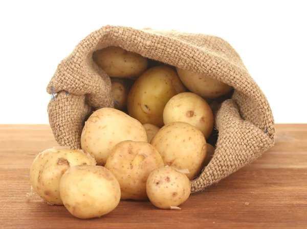Jonge aardappelen in een zak op een tafel op witte achtergrond close-up — Stockfoto