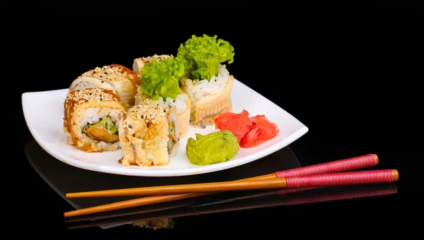 Вкусные рулоны подаются на белой тарелке с палочками для еды, изолированными на черном — стоковое фото