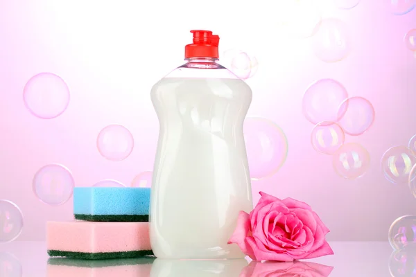 Mytí nádobí se houby a květin na růžovém pozadí — Stock fotografie
