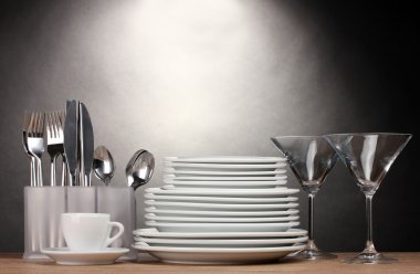 Clean plates, glasses, cup and cutlery on wooden table on grey background clipart