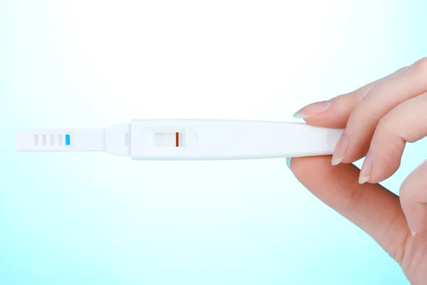 Těhotenský test v ruce na modrém pozadí — Stock fotografie