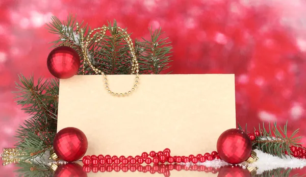 Cartolina bianca, palline di Natale e abete su sfondo rosso — Foto Stock