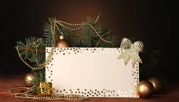 Cartolina bianca, palline di Natale e abete su tavolo di legno su sfondo marrone — Foto Stock