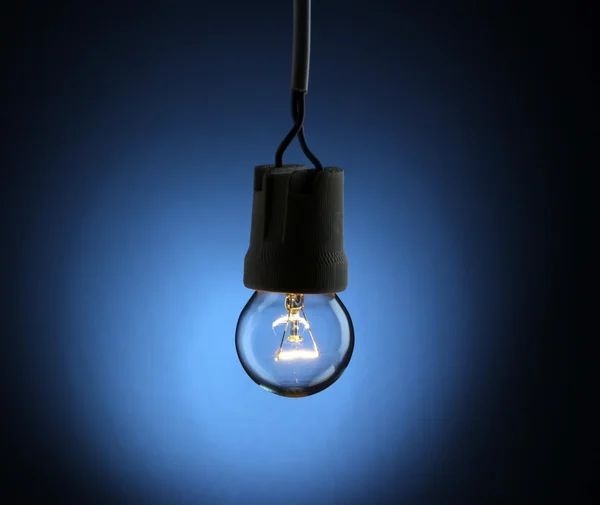 Eine beleuchtete Glühbirne auf blauem Hintergrund — Stockfoto