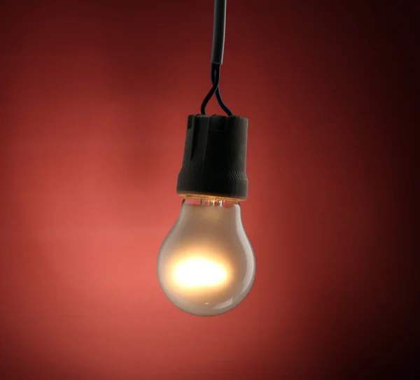A lit light bulb on red background — Stock Photo, Image