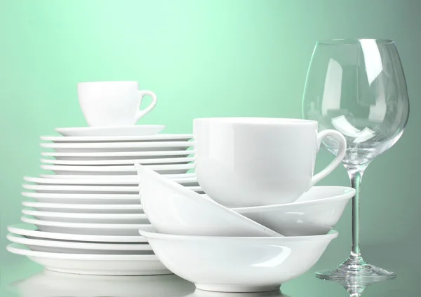 Čisté talíře, šálky a sklenice na zeleném pozadí — Stock fotografie