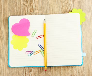 Open note book with stickies and pencil on wooden background clipart