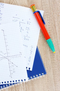 Math, physics and geometry on copybook page on a wooden table clipart