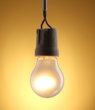 A lit light bulb on yellow background clipart