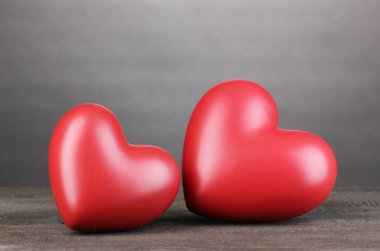Gri arkaplanda tahta masada iki dekoratif kırmızı kalp.