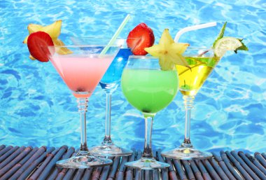 Glasses of cocktails on table on blue sea background clipart