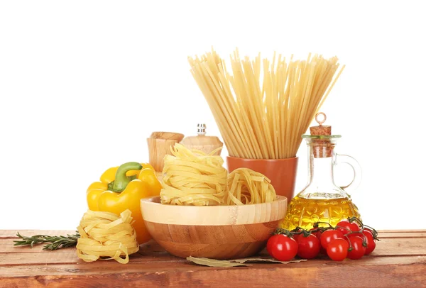 Спагетти, лапша в миске, банка масла и овощей на деревянном столе изолированы на белом — стоковое фото