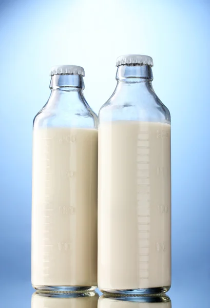 Flaskor av mjölk på blå bakgrund — Stockfoto
