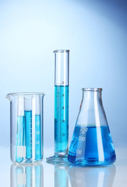Лабораторний скляний посуд з синьою рідиною з відображенням на синьому фоні — стокове фото