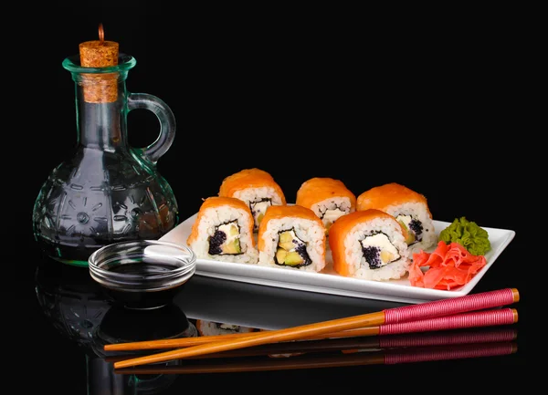 Lekkere broodjes geserveerd op wit bord met stokjes en soja saus geïsoleerd op zwart — Stockfoto