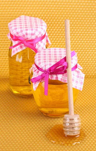 Potten van honing en houten drizzler op gele honingraat achtergrond — Stockfoto