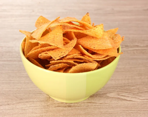 Вкусные картофельные чипсы в зеленой миске на деревянном столе — стоковое фото