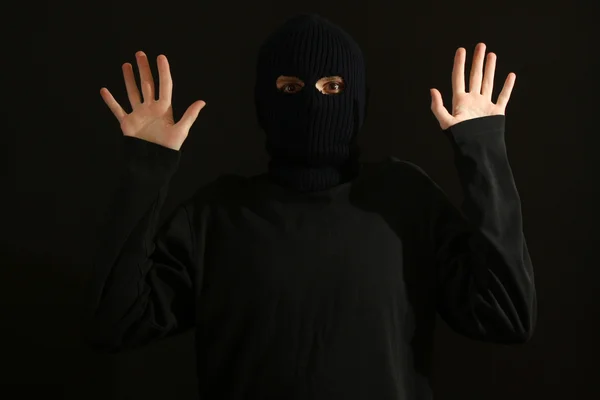 Bandido cercado e preso em máscara preta isolada em preto — Fotografia de Stock
