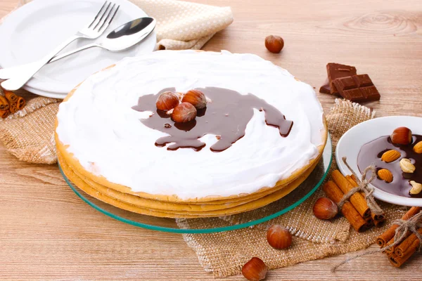 Cake on glass stand and nuts on wooden table — Stock Photo, Image
