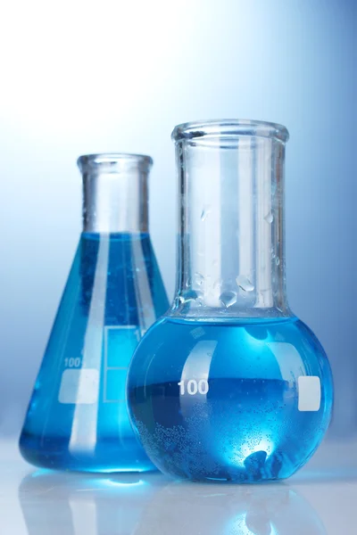 Zkumavky s modrou tekutinou na modrém pozadí — Stock fotografie