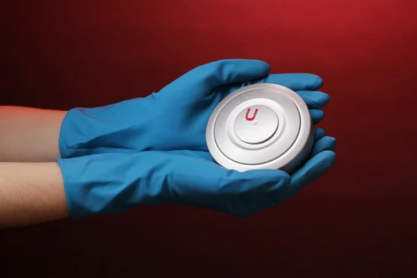 Uran in der Hand auf rotem Hintergrund — Stockfoto