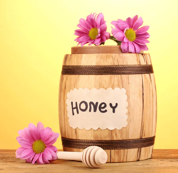 Miel dulce en barril con rociador sobre mesa de madera sobre fondo amarillo —  Fotos de Stock