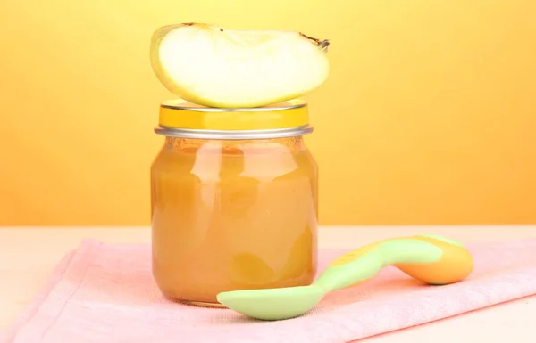 Jar of baby puree with spoon on on napkin on yellow background — Stok Foto