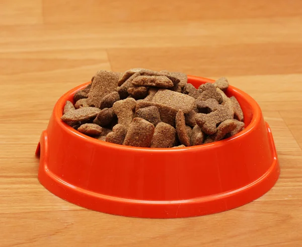 Comida de cão seco em tigela de laranja no chão — Fotografia de Stock