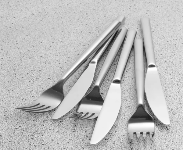 Πιρούνια και μαχαίρια στο μαρμάρινο τραπέζι — Φωτογραφία Αρχείου