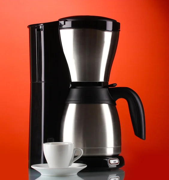 Pembuat kopi dengan cangkir putih dengan latar belakang merah — Stok Foto