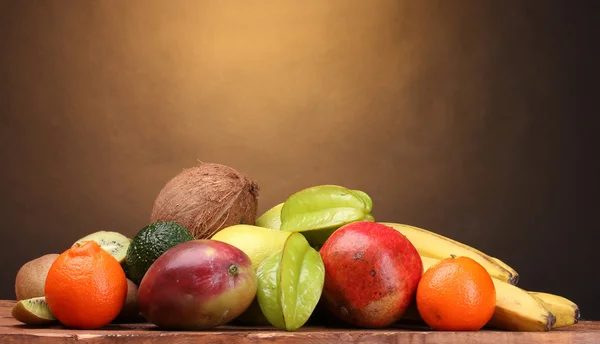 Ассортимент экзотических фруктов на деревянном столе на коричневом фоне — стоковое фото
