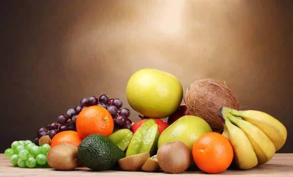 Assortimento di frutti esotici su tavolo di legno su sfondo marrone — Foto Stock