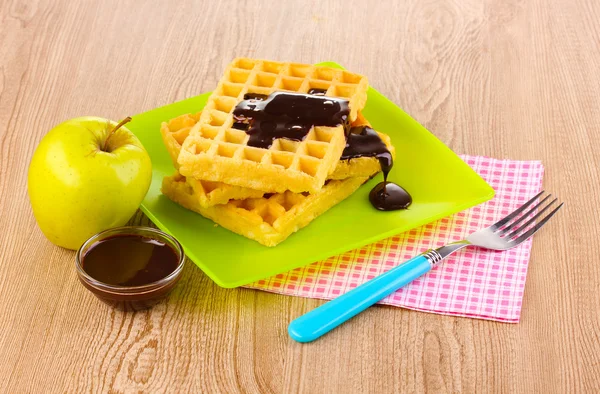 Tasty waffles with chocolate on plate on wooden background — Stock Photo, Image