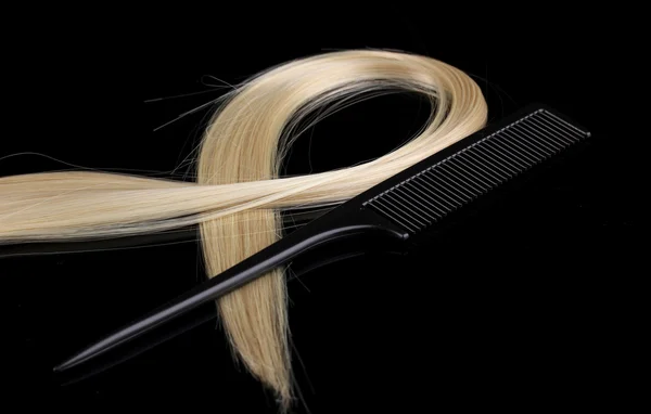 Shiny blond hair and comb isolated on black — Stock Photo, Image