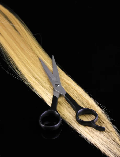 Cabello rubio brillante y tijeras de corte de pelo aisladas en negro — Foto de Stock