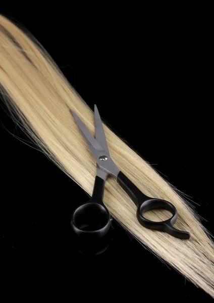 Cabelo loiro brilhante e tesouras de corte de cabelo isolado em preto — Fotografia de Stock