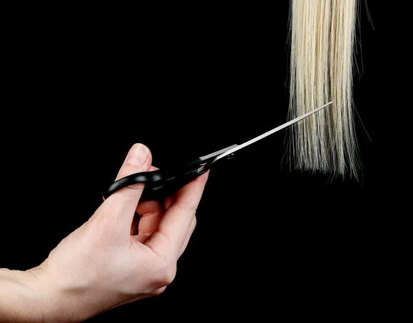 Glanzende blond haar in handen van de kapsalon geïsoleerd op zwart — Stockfoto
