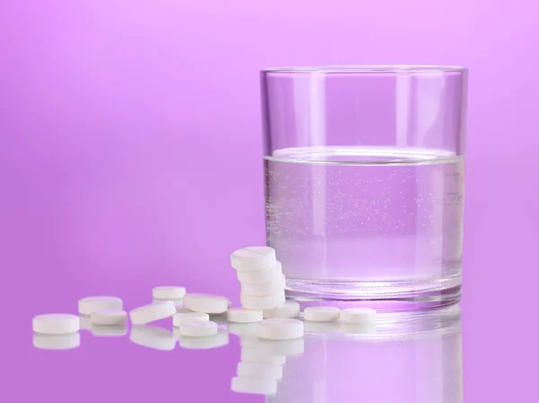 水、紫色の背景に錠剤のガラス — ストック写真