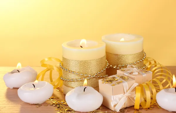 美しいキャンドル、ギフト、黄色の背景に木製のテーブルの装飾 — ストック写真