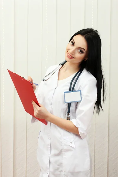 Young beautiful doctor handing folder and write — Stock Photo, Image