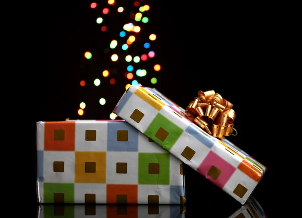 Open gift box with bokeh background on black — Stock Photo, Image