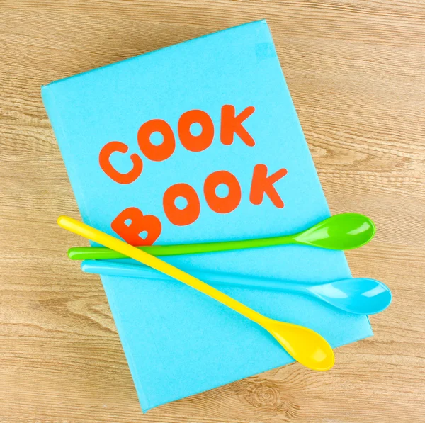 Livro de receitas e utensílios de cozinha sobre fundo de madeira — Fotografia de Stock
