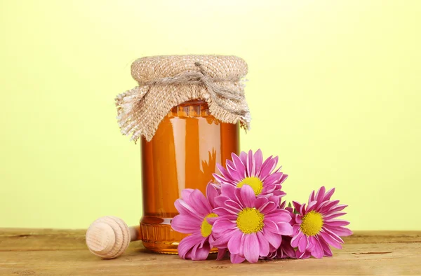 Sweet honey in jar with drizzler on wooden table on green background — Stock Photo, Image