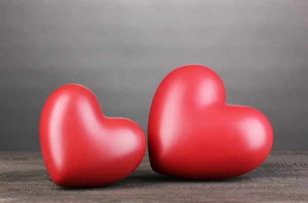 Två dekorativa röda hjärtan på träbord på grå bakgrund — Stockfoto
