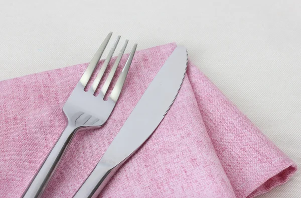 Forchetta e coltello su tovagliolo rosa isolato su bianco — Foto Stock